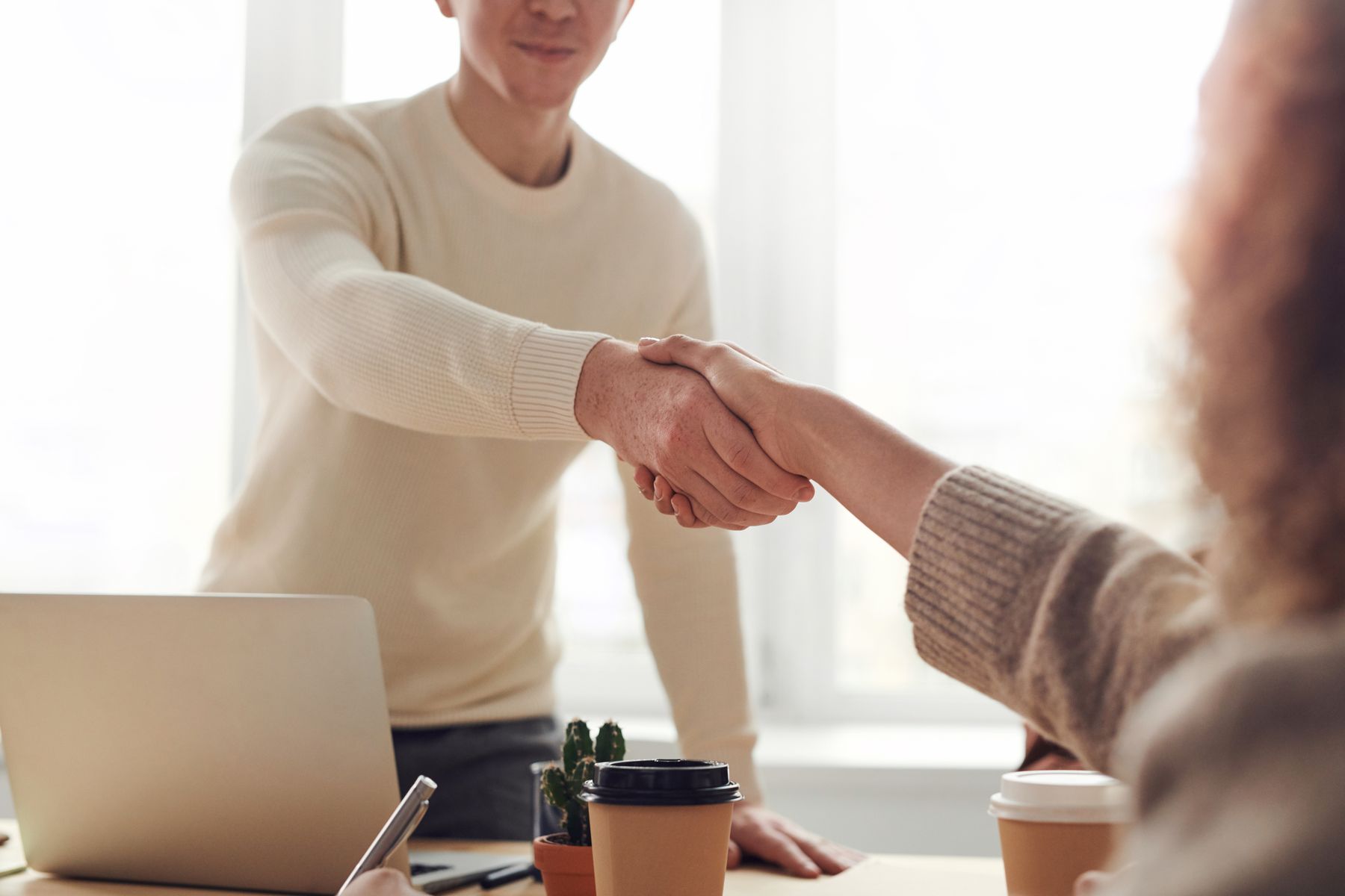 Two professionals shaking hands across a desk